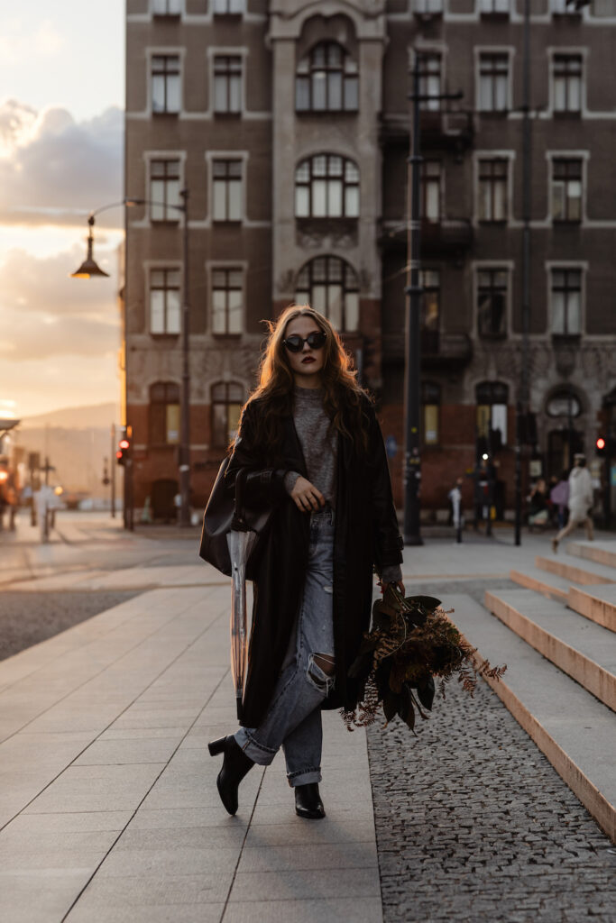 Luxury casual outfits with a long black tailored coat, distressed denim jeans, and black ankle boots for a street-style aesthetic.