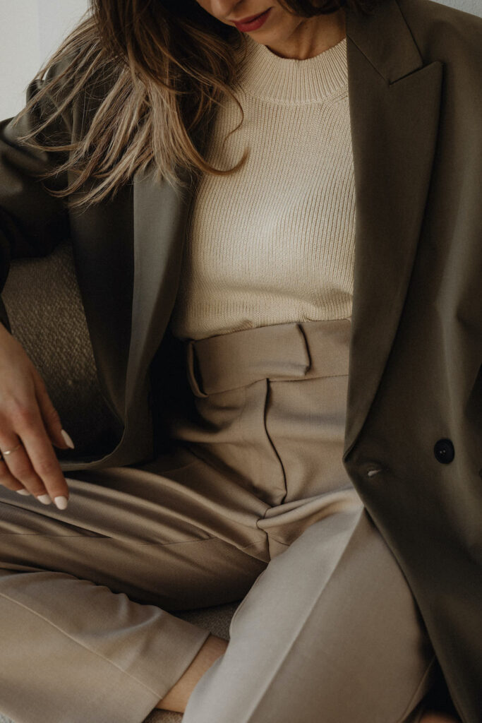 Woman seated wearing a dark blazer and beige trousers form the Spring Work Wear Edit.