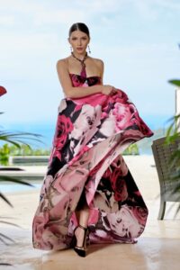 Woman in a luxury casual setting wearing a bold pink and black floral print maxi dress with a halter neckline.