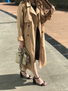 A woman wearing a light-caramel trench coat and a handbag.