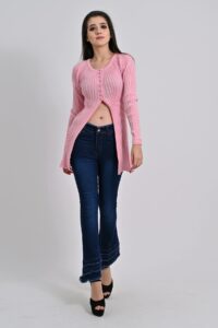 A model wearing a pink knit ribbed top with dark wash denim jeans and platform black heels.