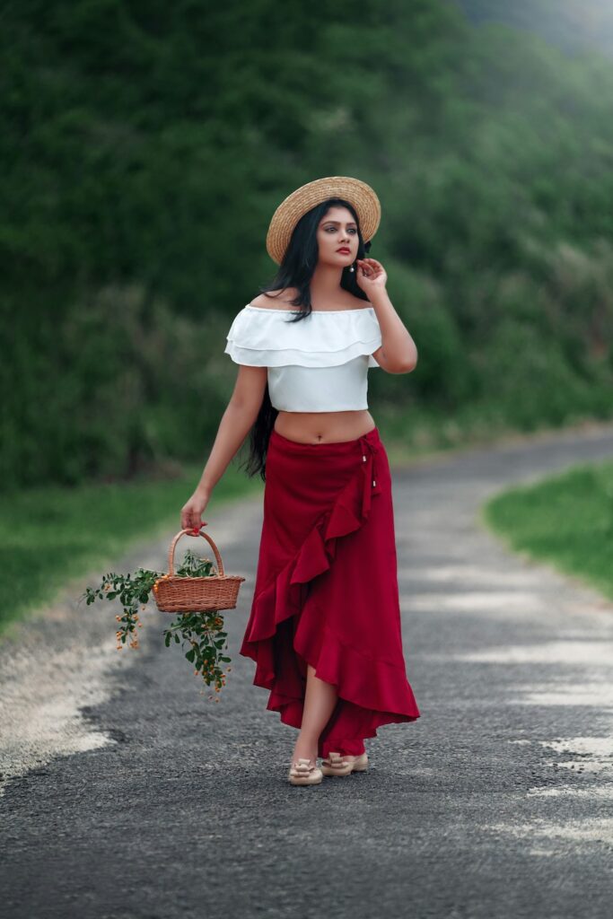 Luxury casual outfits with a vibrant red ruffled maxi skirt, white off-the-shoulder crop top, and a classic straw hat.
