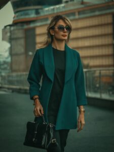 For our Spring Work Wear Edit, we showcase the curated edit of a professional woman wearing a teal softly tailored jacket over a black top, carrying a black leather handbag. 
