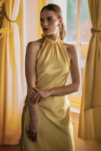 A woman wearing a yellow silk halter-neck dress.