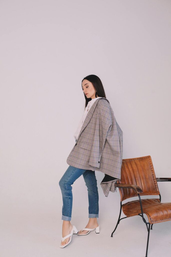 Modern blazer outfit for women styling a checkered modern blazer over the shoulders with blue jeans for an elevated smart casual look.